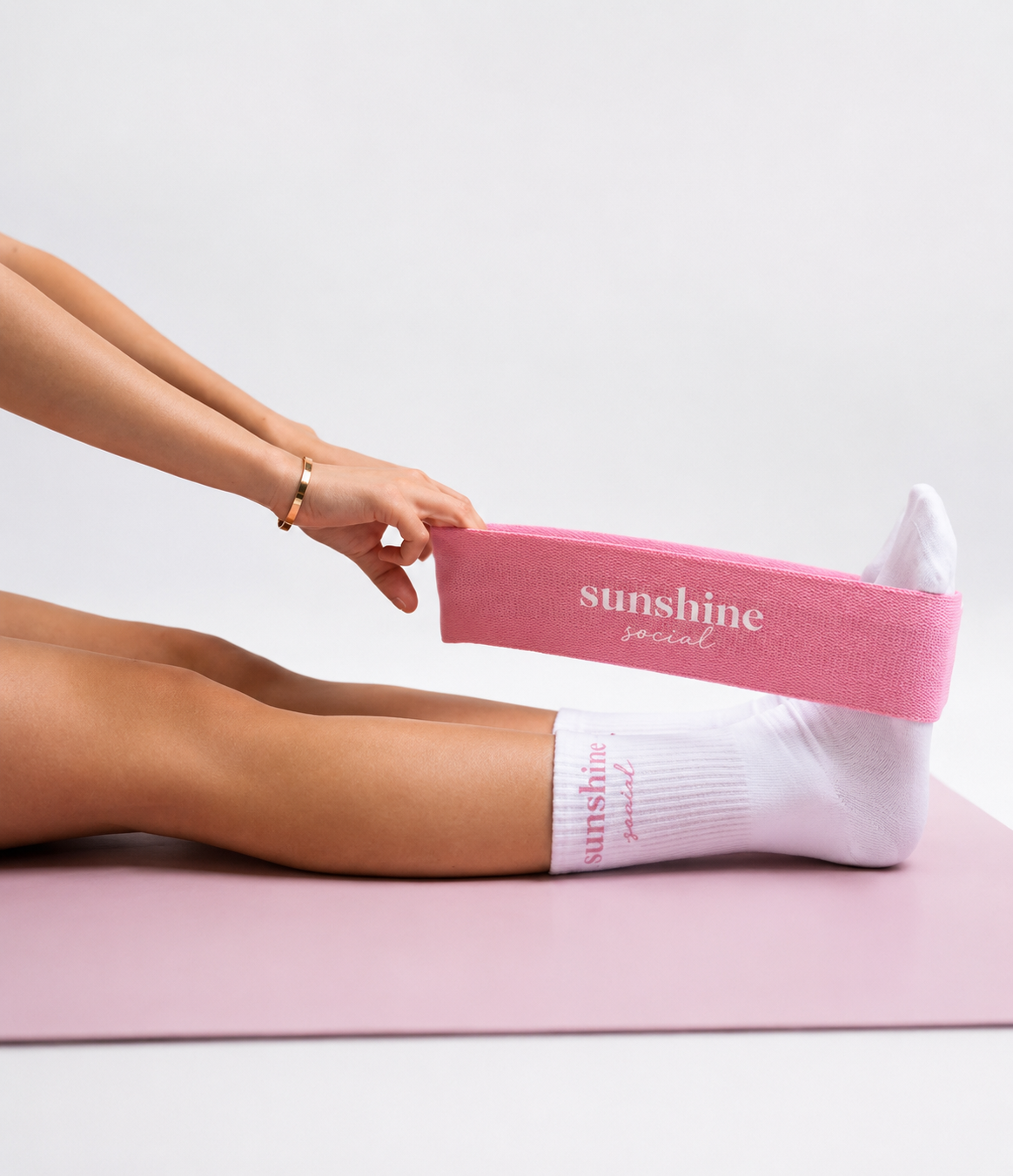 Sunshine Social branded resistance band and socks on a soft pink yoga mat